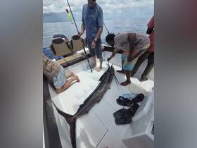 A group of anglers celebrates their catch aboard a fishing boat, showcasing the thrill of deep-sea fishing adventures.