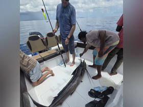 A group of anglers celebrates their catch aboard a fishing boat, showcasing the excitement of a successful fishing trip in open waters.