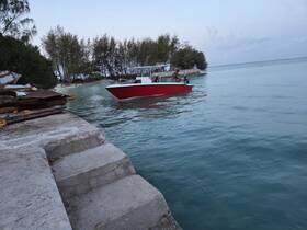 A red boat approaches the dock in calm waters, showcasing a serene moment in a picturesque setting, perfect for exploring coastal destinations.