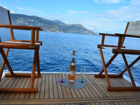 A serene setup featuring elegant seating and a bottle of wine on deck, perfect for relaxing moments on the water with stunning views.