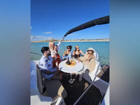 A lively group enjoys cocktails on a yacht, celebrating under the sun with stunning turquoise waters in the background — perfect for a fun day out on the water.