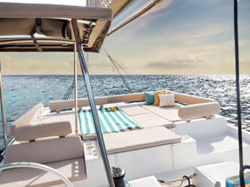 A beautifully designed lounge area on a catamaran, featuring comfortable seating and a vibrant striped mat, perfect for relaxing while enjoying the ocean views.