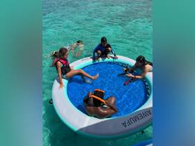 A group of children enjoys a fun day of snorkeling and swimming in a floating pool, surrounded by crystal-clear waters — perfect for family adventures.