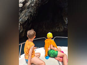 Two children eagerly explore a cave entrance from the deck of a boat, showcasing the excitement of adventure on the water.