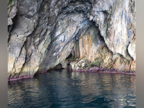 A stunning view of a rocky cave formation reflected in calm waters, showcasing the natural beauty of coastal landscapes — perfect for adventure seekers and nature lovers.