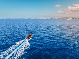 Aerial view of a boat cruising through vibrant blue waters, showcasing the beauty of maritime adventures.