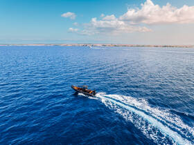 A dynamic shot of a speedboat cruising through vibrant blue waters, showcasing the thrill of on-water adventures and exploration.
