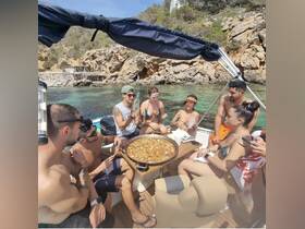 A lively group enjoys a delicious paella on a boat, creating unforgettable memories in a stunning coastal setting.