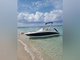 A sleek speedboat anchored on a sandy beach, showcasing its stylish design against a backdrop of clear waters and fluffy clouds.
