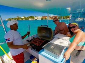 A lively scene aboard a boat as a chef grills hot dogs while guests enjoy drinks and smiles, capturing the essence of a fun day on the water.