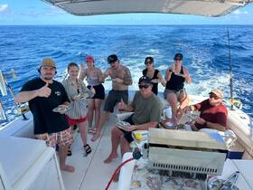 A lively group enjoys a meal aboard a fishing boat, showcasing camaraderie and fun on the water — perfect for memorable outings and celebrations.