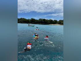 A group enjoys snorkeling in clear waters, showcasing the excitement of on-water activities against a beautiful beach backdrop.