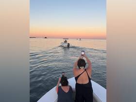 Two friends capture the stunning sunset while enjoying a boat ride, creating memorable moments on the water.