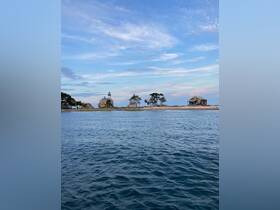 A picturesque view of a coastline featuring a lighthouse and charming buildings, perfect for showcasing scenic destinations during boating trips.