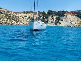 A stunning view of a sailboat anchored in crystal-clear waters, with rocky cliffs in the background, perfect for showcasing sailing adventures.