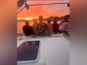 A group of friends enjoys a stunning sunset aboard a boat, creating unforgettable memories against a vibrant sky.