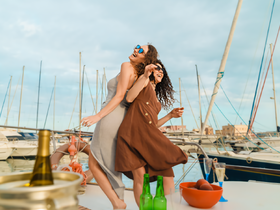 Two friends joyfully celebrate on the deck of a yacht, embodying the perfect party atmosphere on the water.