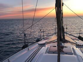 A stunning view from the bow of a sailboat at sunset, showcasing the tranquil waters and colorful sky — perfect for sailing enthusiasts and sunset lovers.