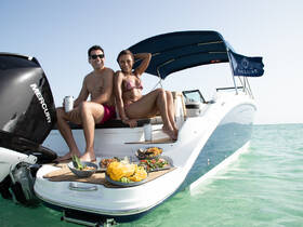 A couple enjoys a delightful meal on the deck of a luxurious yacht, showcasing a perfect day on the water with delicious food and refreshing drinks.
