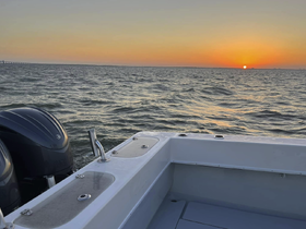 A serene view of a boat's edge with the sun setting over the water, creating a picturesque backdrop for evening cruises.