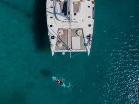 An aerial view captures a lively scene with guests enjoying paddleboarding near a catamaran, showcasing the vibrant turquoise waters perfect for water activities.