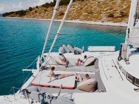 A group of friends relaxes on the deck of a catamaran, enjoying the stunning turquoise waters — the perfect setting for a day of sunbathing and leisure.