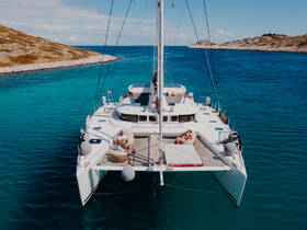 Aerial view of a catamaran with a couple relaxing on deck, surrounded by stunning turquoise waters — an idyllic setting for a romantic getaway or leisure cruise.