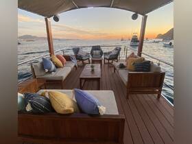 A cozy lounge area on a boat featuring comfortable seating and decorative pillows, perfect for relaxing while enjoying scenic views at sunset.