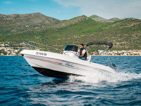 A speedboat navigates through the sparkling waters with a driver at the helm, showcasing the thrill of boating adventures in a scenic coastal setting.