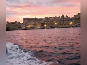 A stunning sunset view over the coastline of Malta, showcasing the historic architecture illuminated by warm lights — a perfect backdrop for evening boat tours.
