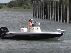 A person operates a fishing boat on the water, showcasing an active fishing experience. Perfect for those looking to enjoy a day on the water.