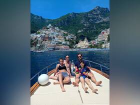 A family enjoys a sunny day on a boat, relaxing and taking in the stunning coastal views — perfect for memorable vacations along the Amalfi Coast.