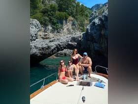 A joyful group enjoys a sunny day on a boat, posing together against a stunning rocky backdrop — perfect for family outings and summer adventures.