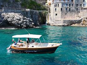 A scenic view of a boat tour along the Amalfi Coast, showcasing guests enjoying their time on the water against a stunning coastal backdrop.