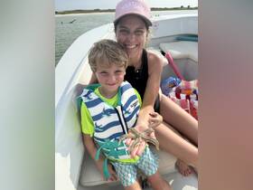 A joyful moment as a mother and her son hold a starfish on a boat, showcasing a delightful human-animal interaction during their aquatic adventure.
