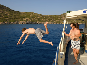 A thrilling moment captured as a guest dives off the boat into the sparkling blue waters, showcasing the fun and excitement of a day on the water with friends.