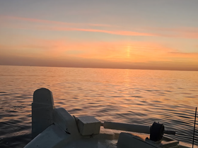 A serene sunset view from the bow of a boat, showcasing calm waters and vibrant colors — perfect for peaceful evening cruises.