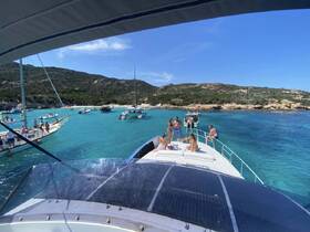 A lively group enjoys a sunny day on a yacht, surrounded by turquoise waters and other boats, perfect for beach parties and fun in the sun.