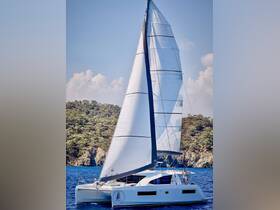 A sleek catamaran sails gracefully through clear waters, showcasing its impressive design and vibrant sails — perfect for sailing enthusiasts and charter adventures.
