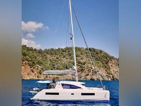 A sleek Leopard 40 catamaran glides through clear waters, showcasing its elegant design against a stunning natural backdrop.