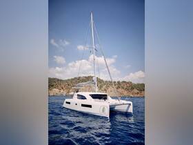 A sleek catamaran sails through clear waters, showcasing its elegant design against a picturesque backdrop of hills — perfect for luxury sailing adventures.