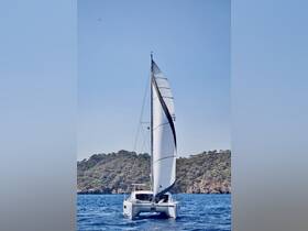 A stunning catamaran sails gracefully through clear waters, showcasing its elegant design against a backdrop of lush greenery.