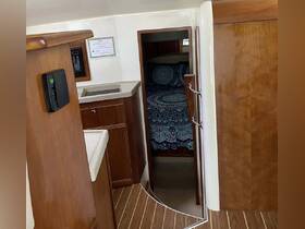 A cozy interior view of a boat cabin featuring a well-appointed kitchenette and a comfortable sleeping area, perfect for relaxing during a nautical getaway.