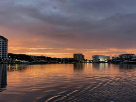 A stunning sunset reflects off calm waters, showcasing the beautiful skyline and marina — a perfect backdrop for evening boat trips and scenic views.