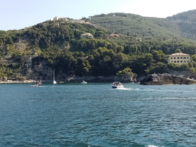 A picturesque view of multiple boats navigating along a stunning coastline, showcasing the beauty of the landscape and the joy of on-water activities.