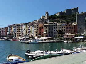 A picturesque harbor scene featuring colorful buildings and various boats, capturing the vibrant atmosphere of coastal life.