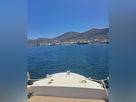 A clear view from the front of a boat cruising on calm waters, with a scenic backdrop of mountains and a coastal town, perfect for exploring beautiful destinations.