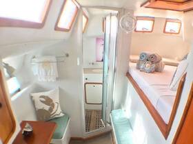 A cozy interior view of a boat cabin featuring a comfortable seating area, neatly arranged towels, and a bathroom, perfect for relaxing during a sailing trip.