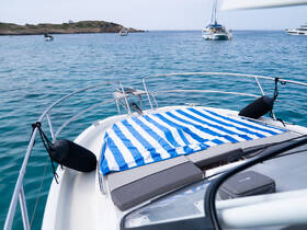 A serene view from the front of a yacht, showcasing a striped cover on the deck and calm turquoise waters in the background — perfect for a relaxing day on the water.