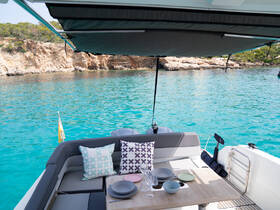 A cozy interior view of a boat's seating area, featuring stylish cushions and a dining table set for a relaxing day on the water.